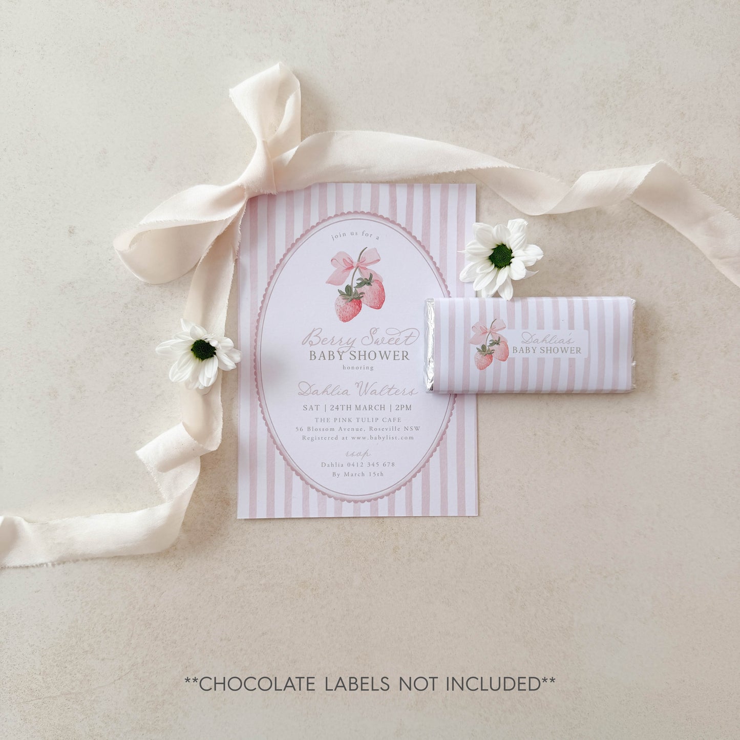 Baby shower invitation with pink and white striped design, accompanied by a candy bar on a light background.