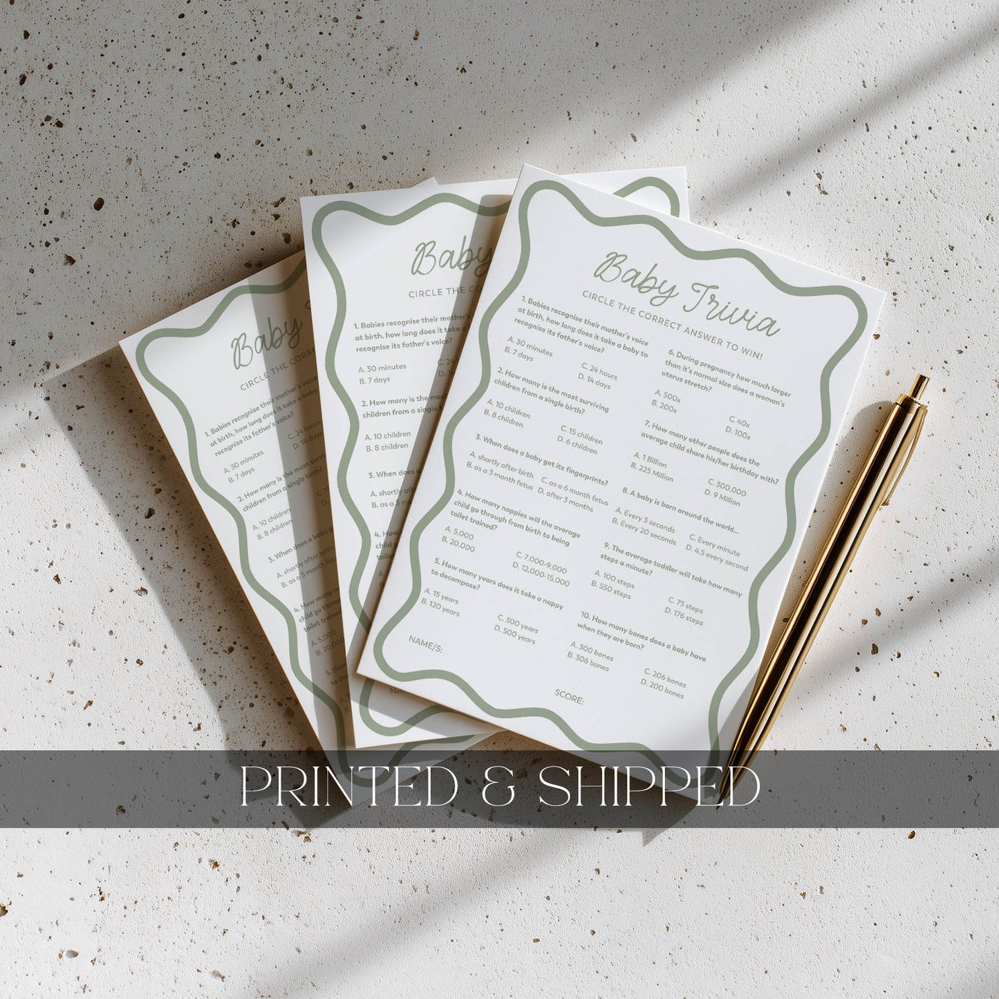 Three baby shower questionnaires on a textured surface with a pen.