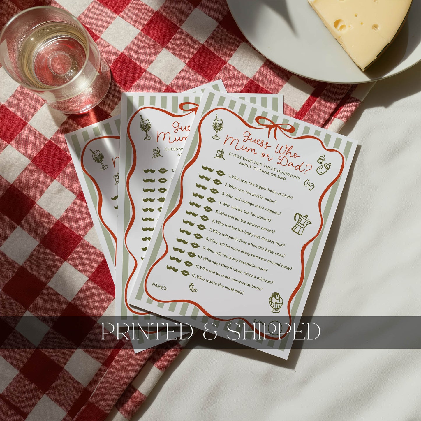 Ciao Baby Two 'Guess Who, Mum or Dad?' cards on a red and white checkered tablecloth with a glass of wine and cheese.