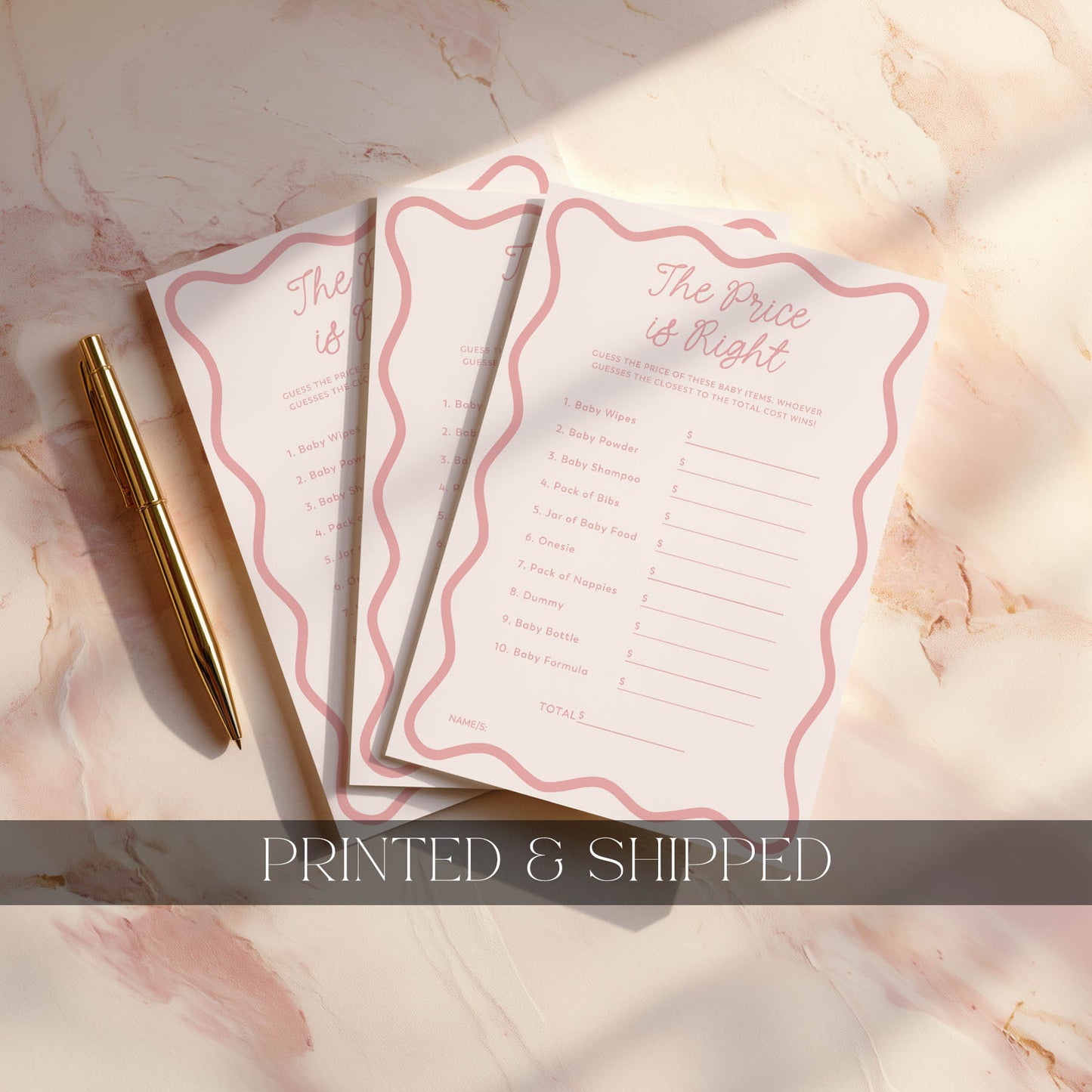 Three pink baby prediction cards on a marble surface with a gold pen.