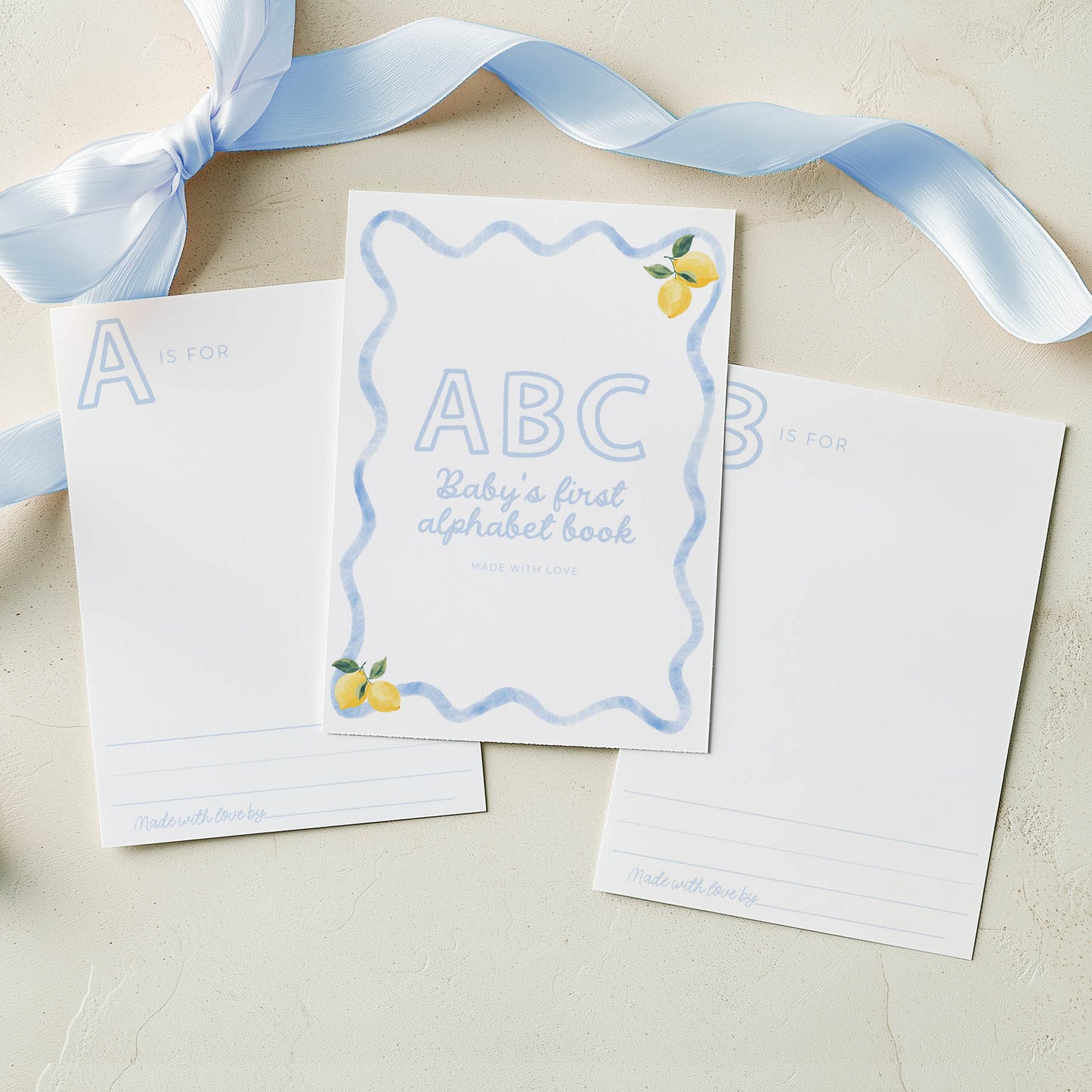 Children's book titled 'ABC Baby's first alphabet book' with a blue ribbon on a beige background