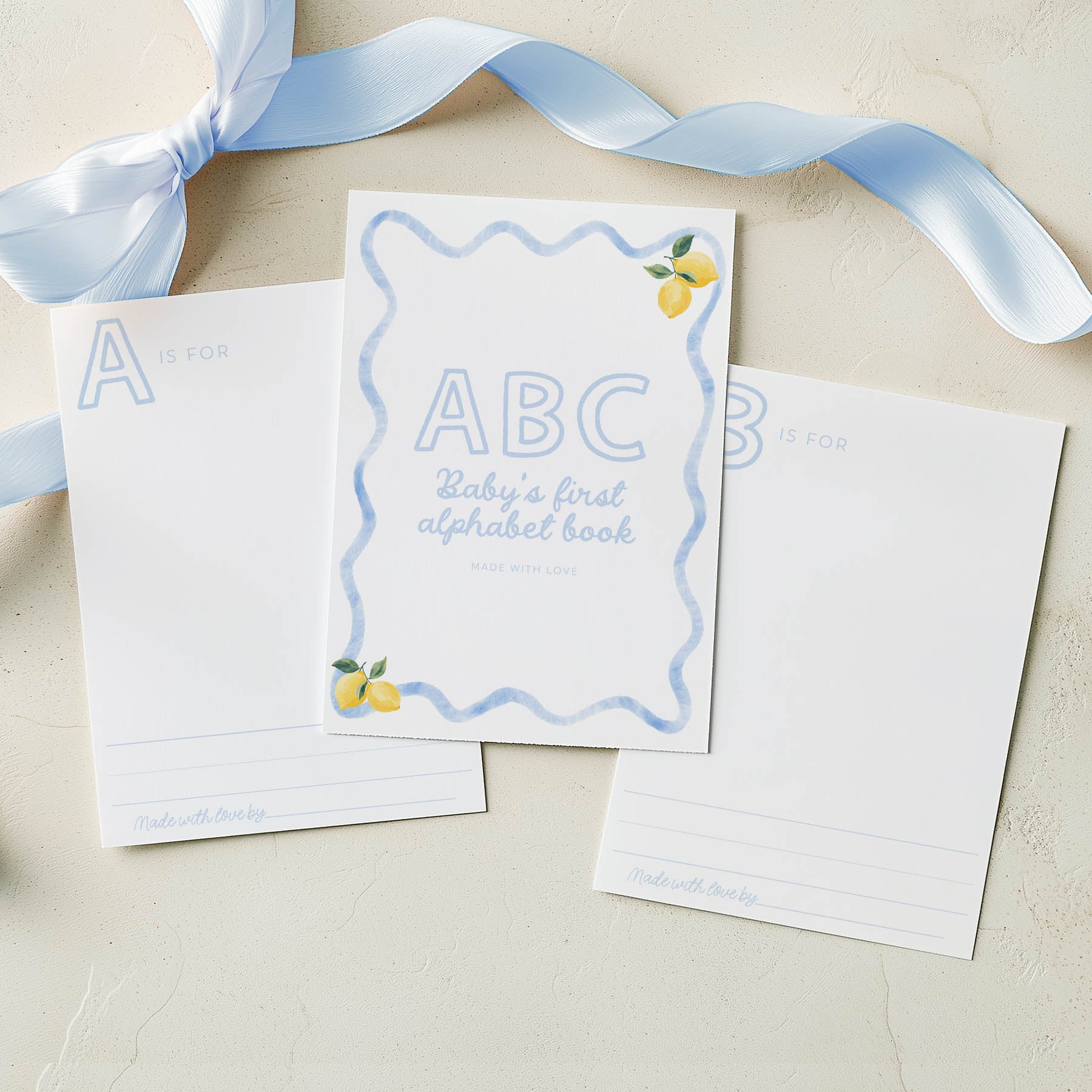 Children's book titled 'ABC Baby's first alphabet book' with a blue ribbon on a beige background