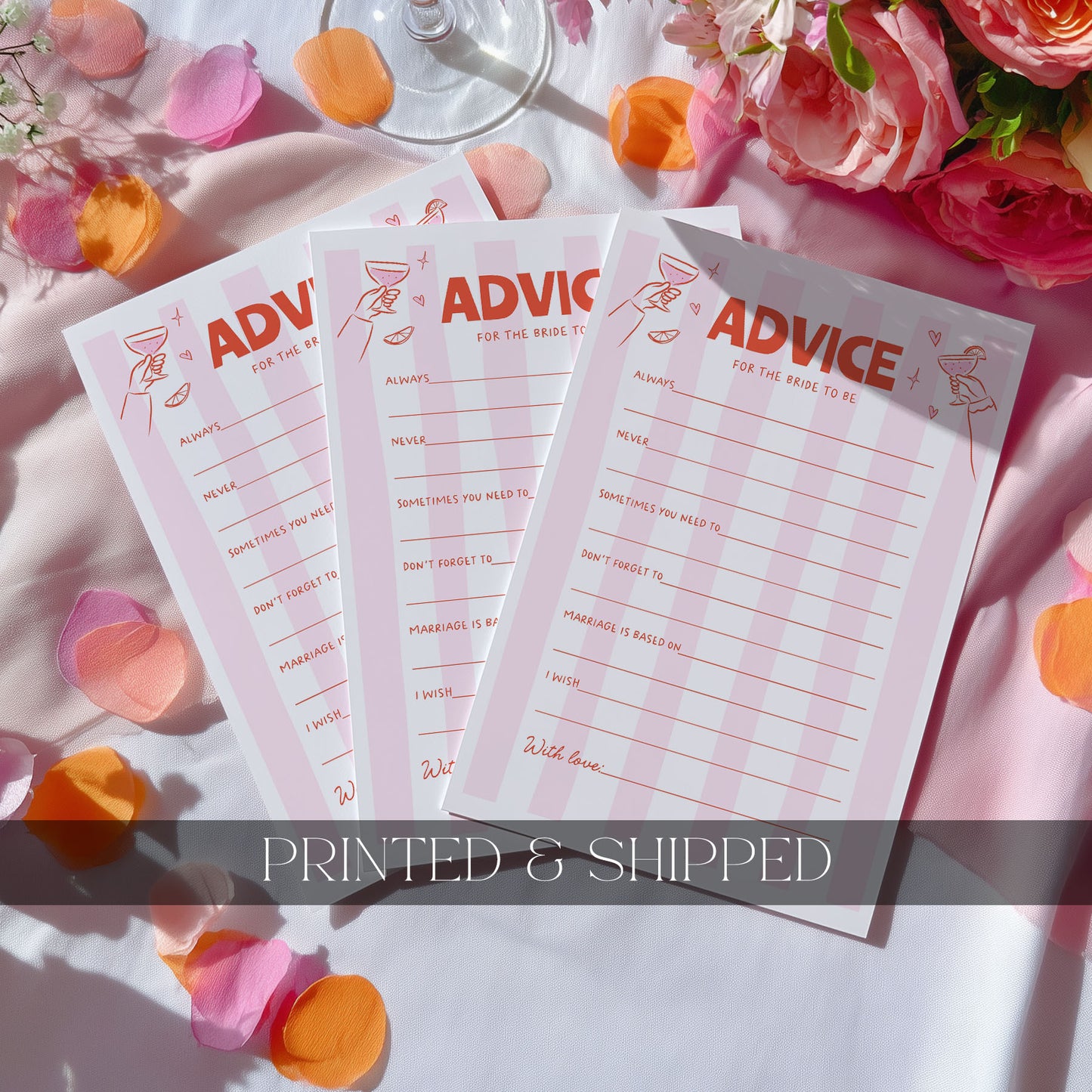 Three pink and white 'ADVICE' notepad sheets fanned out on a white fabric surface with scattered peach and orange flower petals. A wine glass base is visible at the top, and a dark translucent banner across the bottom reads 'PRINTED & SHIPPED'.