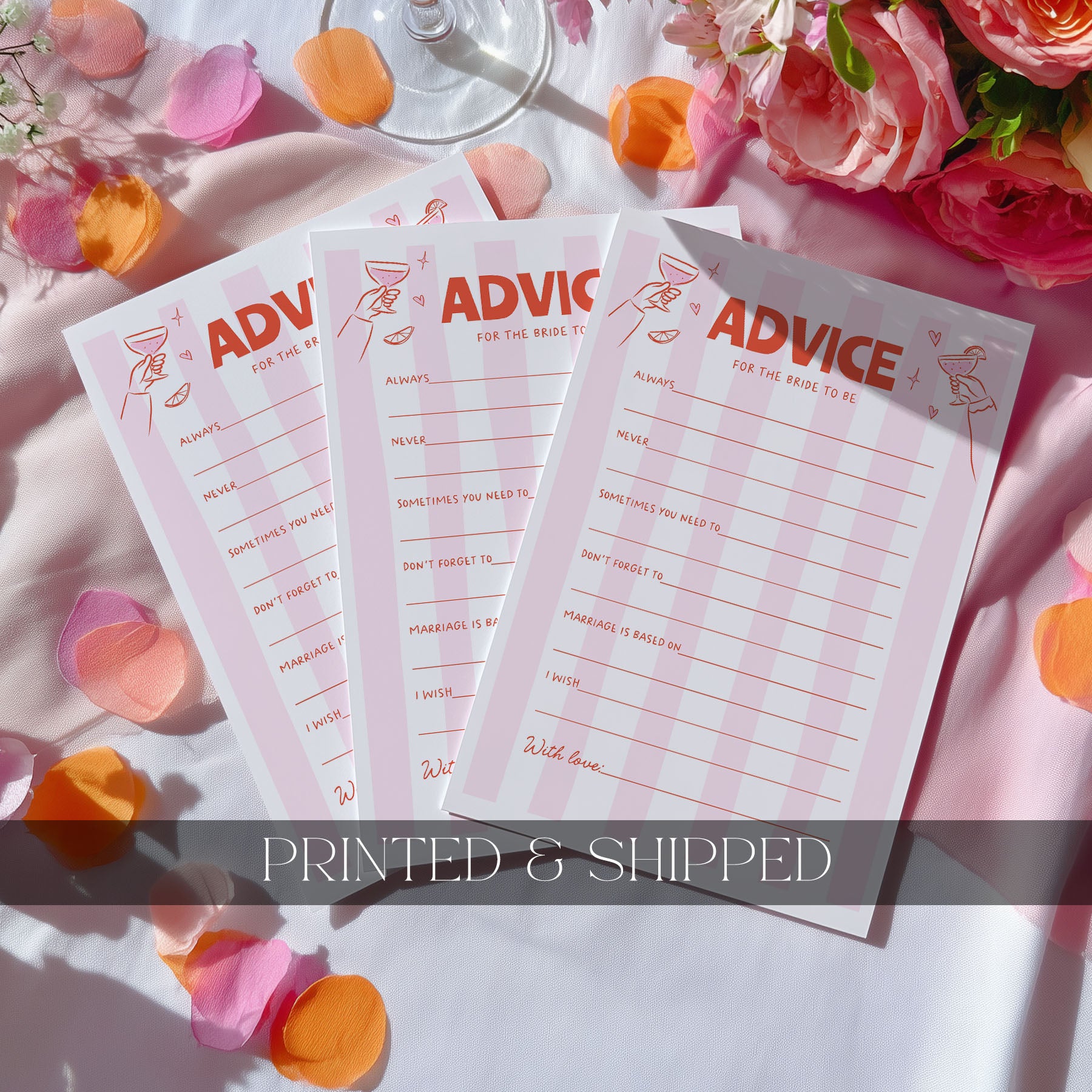 Three pink and white 'ADVICE' notepad sheets fanned out on a white fabric surface with scattered peach and orange flower petals. A wine glass base is visible at the top, and a dark translucent banner across the bottom reads 'PRINTED & SHIPPED'.