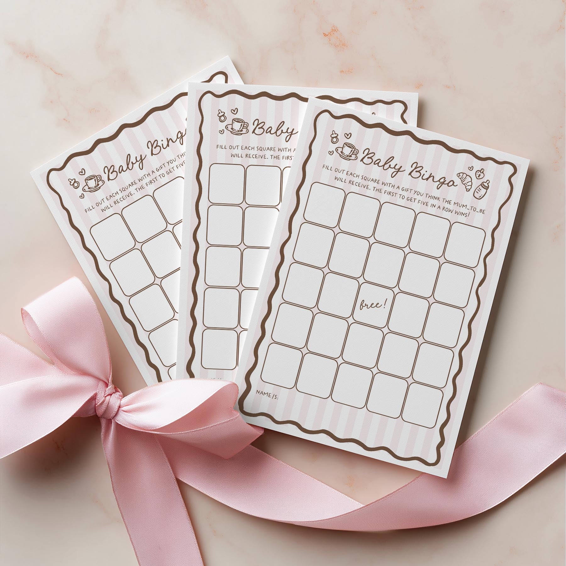 Two baby bingo cards with a pink ribbon on a light background