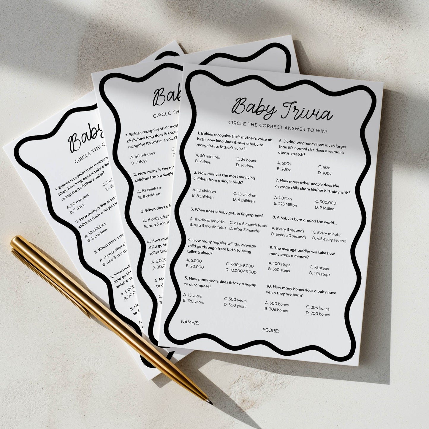 Three baby trivia question cards with a pen on a light surface