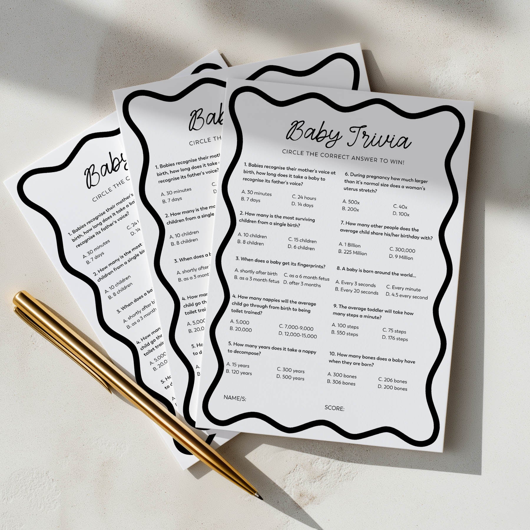 Three baby trivia question cards with a pen on a light surface