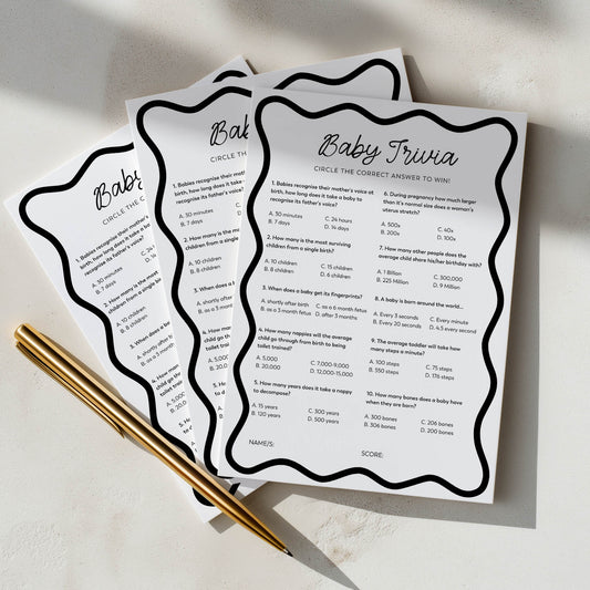 Three baby trivia question cards with a pen on a light surface