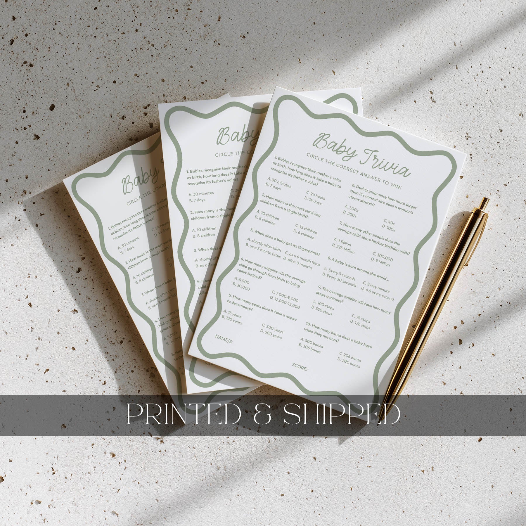 Three baby shower questionnaires on a textured surface with a pen.