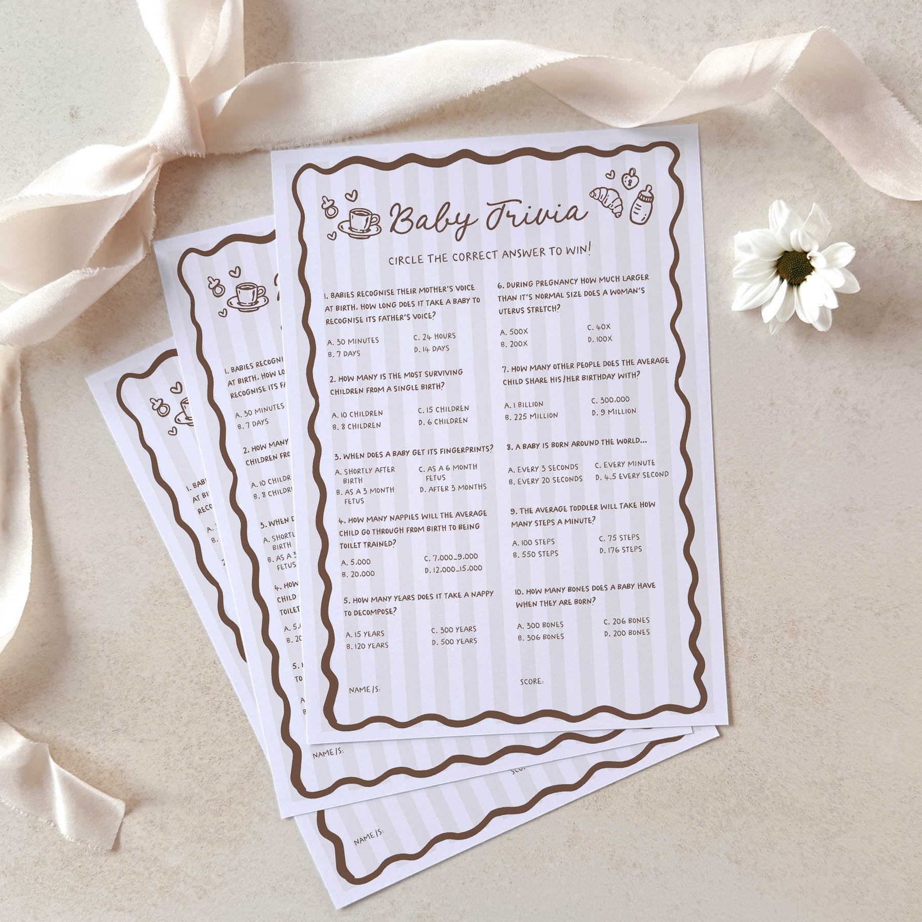 Baby trivia game cards on a light background with ribbons and a flower.