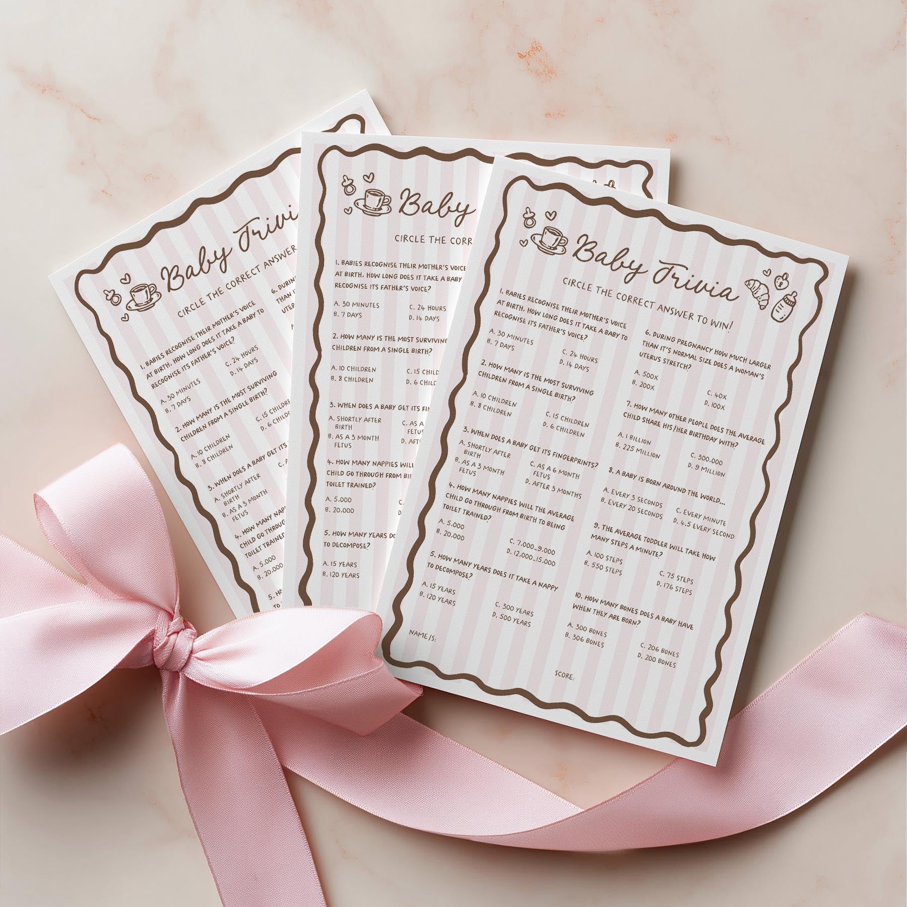 Two baby trivia cards with decorative border on a light pink background with a pink ribbon.