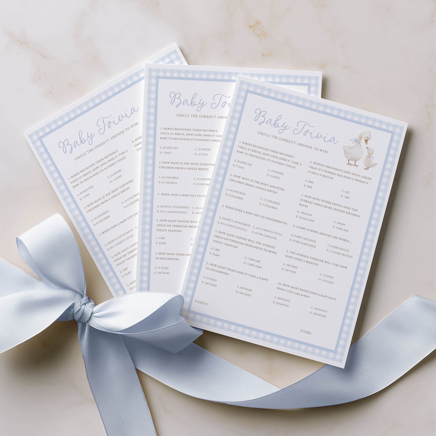Three baby shower invitations with a blue ribbon on a beige background