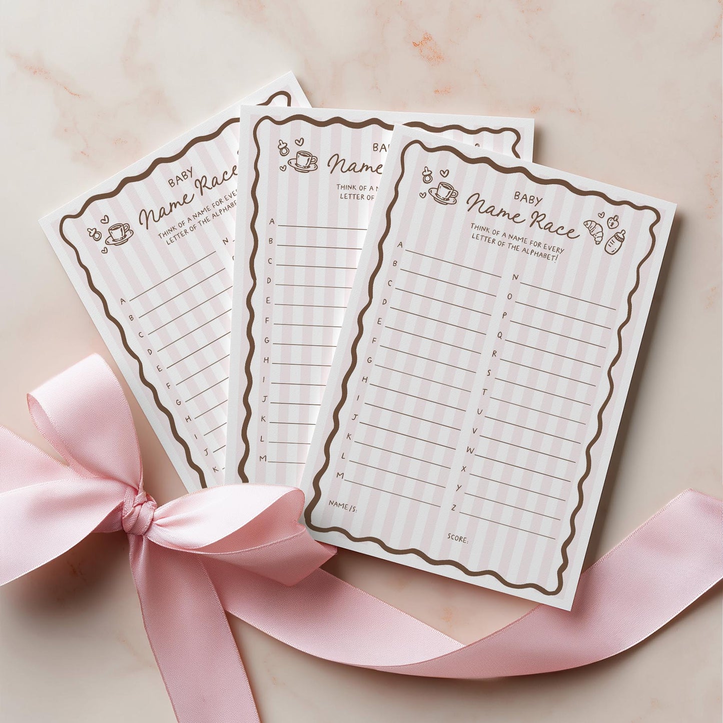 Two baby bingo cards with a pink ribbon on a light background