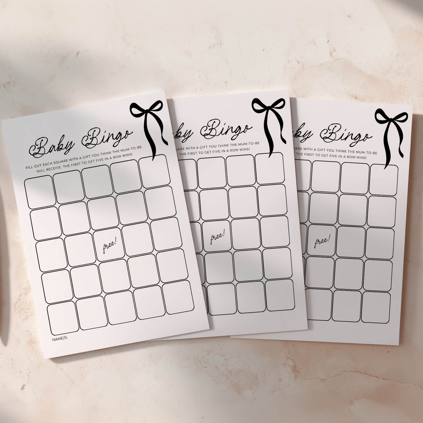 Three black bow baby shower bingo cards on a light surface
