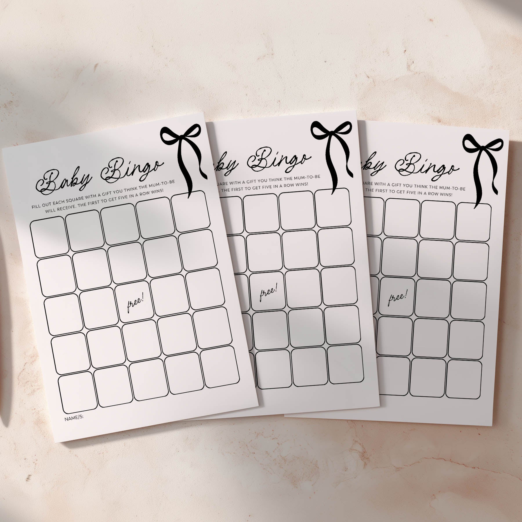 Three black bow baby shower bingo cards on a light surface