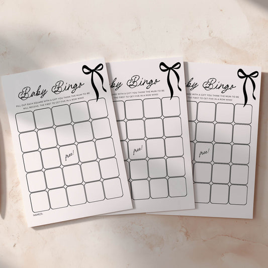 Three black bow baby shower bingo cards on a light surface