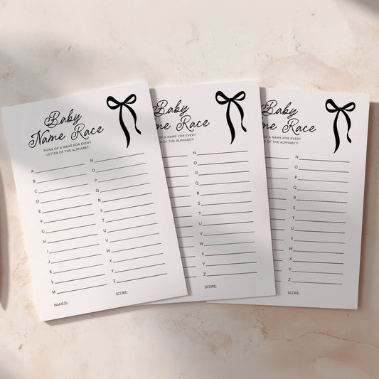 Three black bow baby predictions cards with black ribbons on a light background