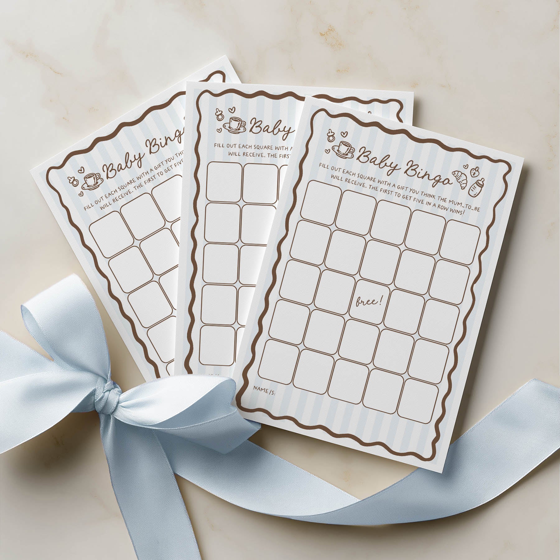 Three baby bingo cards with a decorative blue ribbon on a beige background
