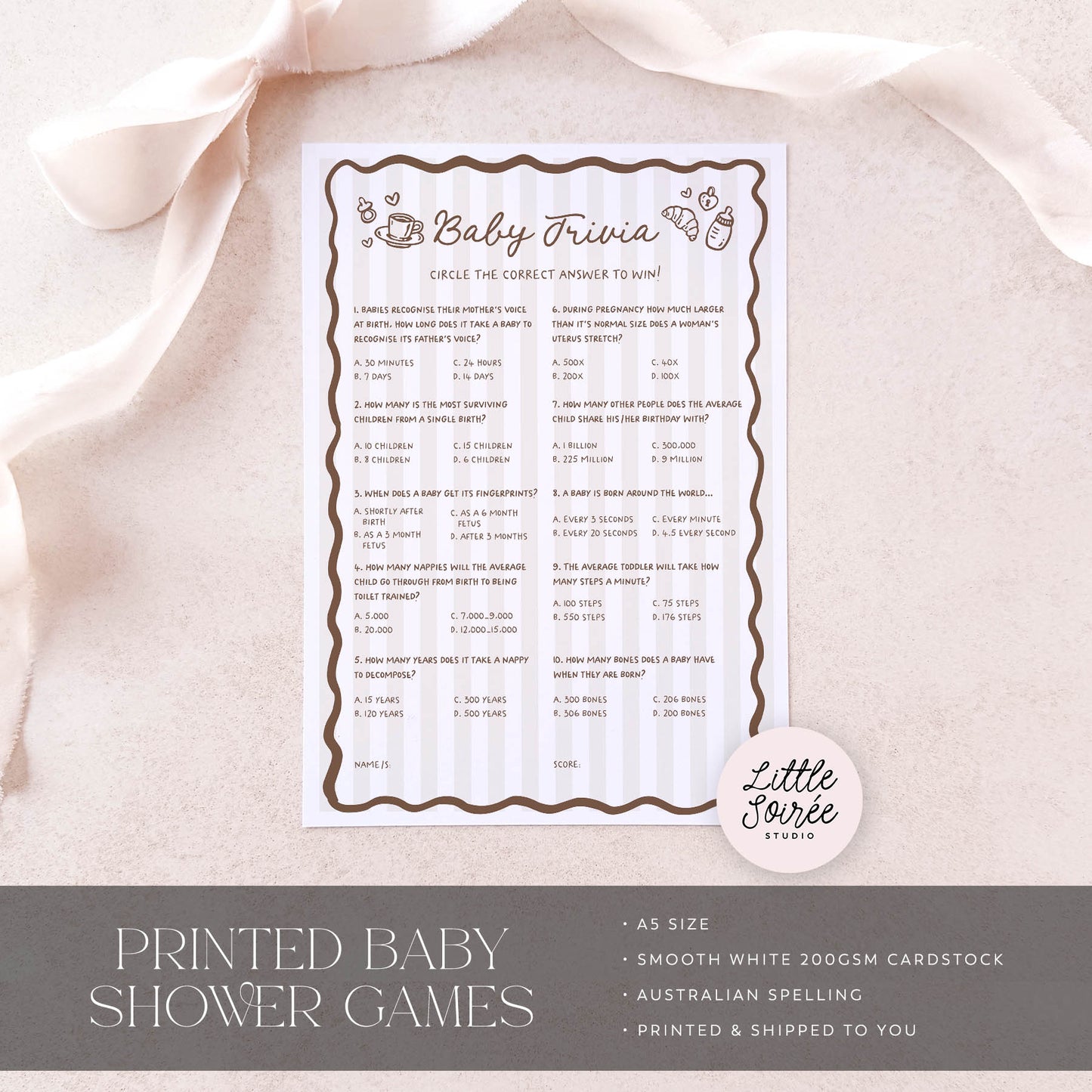 Baby trivia game sheet on a light pink fabric background with 'Little Sourie Studio' branding.