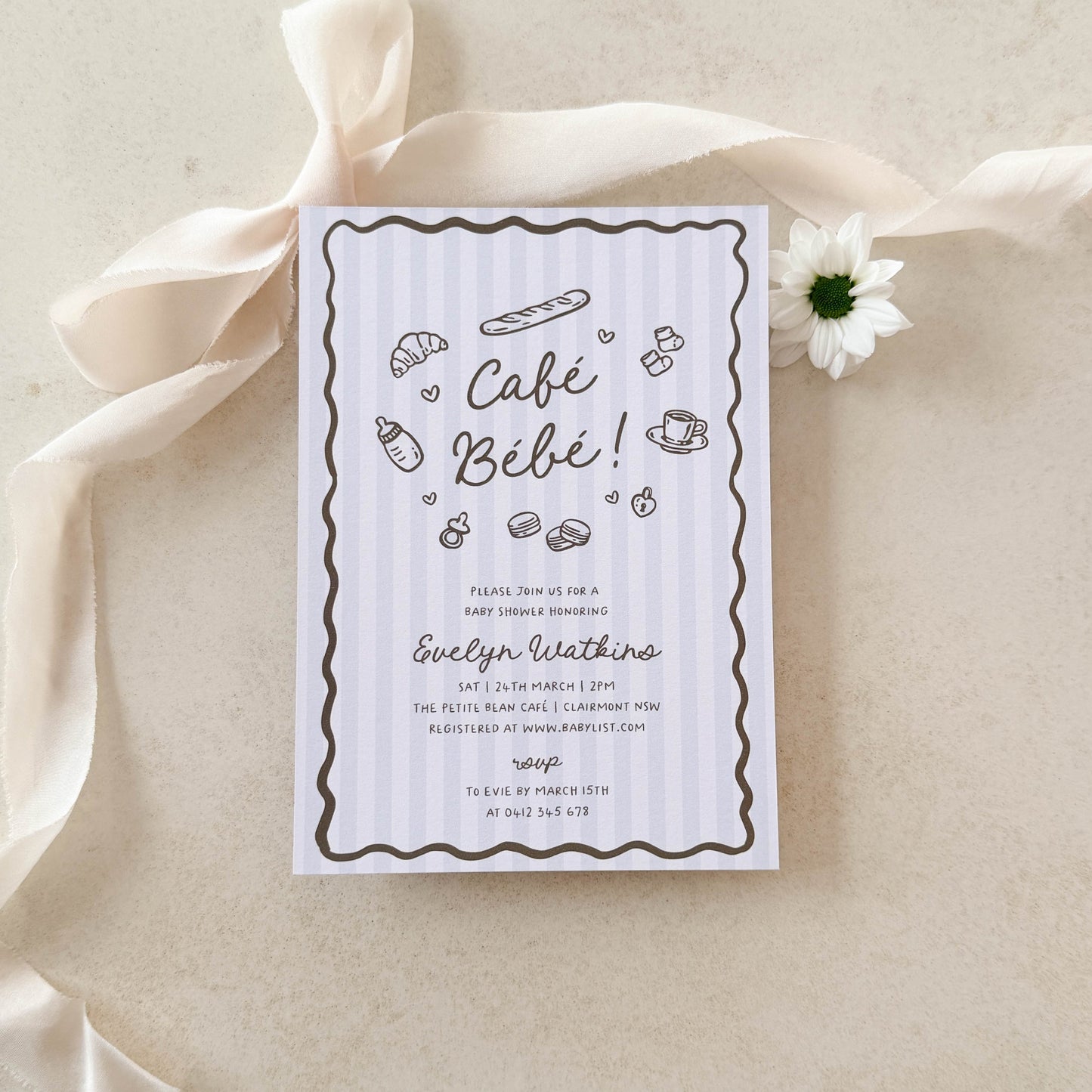 Baby shower invitation with ribbon and flower on a beige background