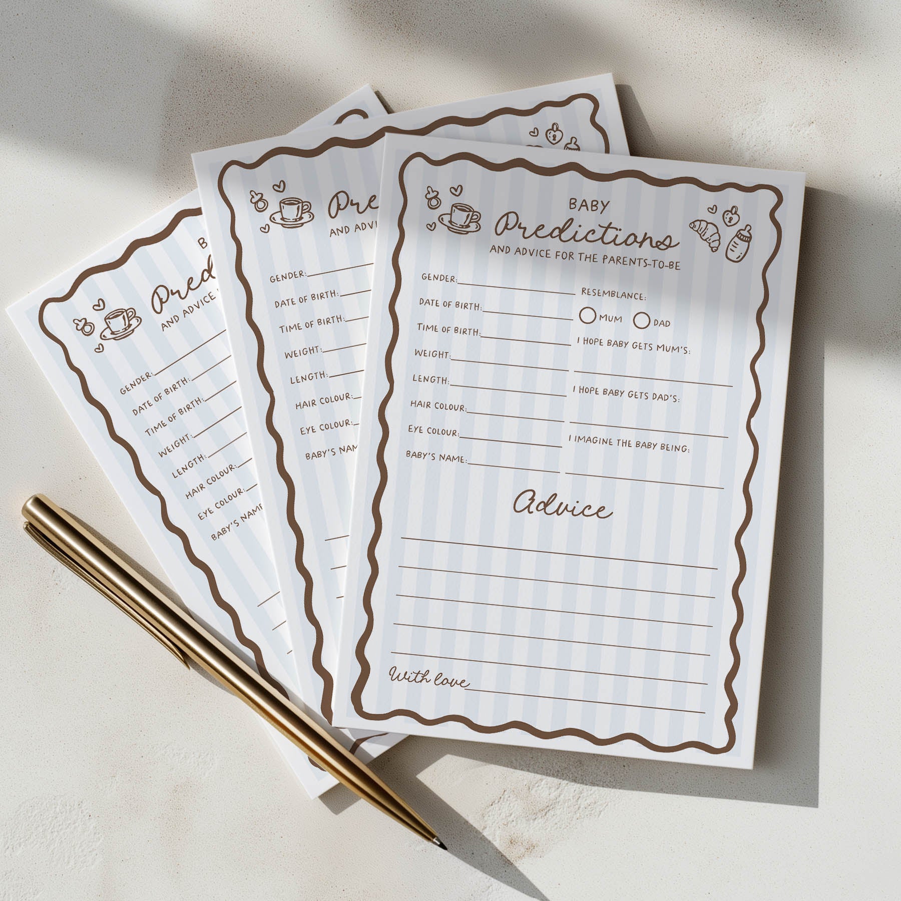Three baby shower prediction sheets with a pen on a light surface