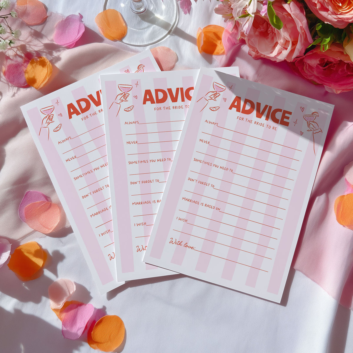 Three printed cards titled "ADVICE FOR THE BRIDE" arranged on a white draped surface with pink and orange flower petals and flowers around them.