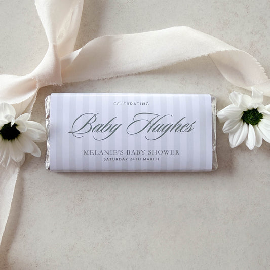 Baby shower chocolate bar favour with ribbon and flowers on a light background