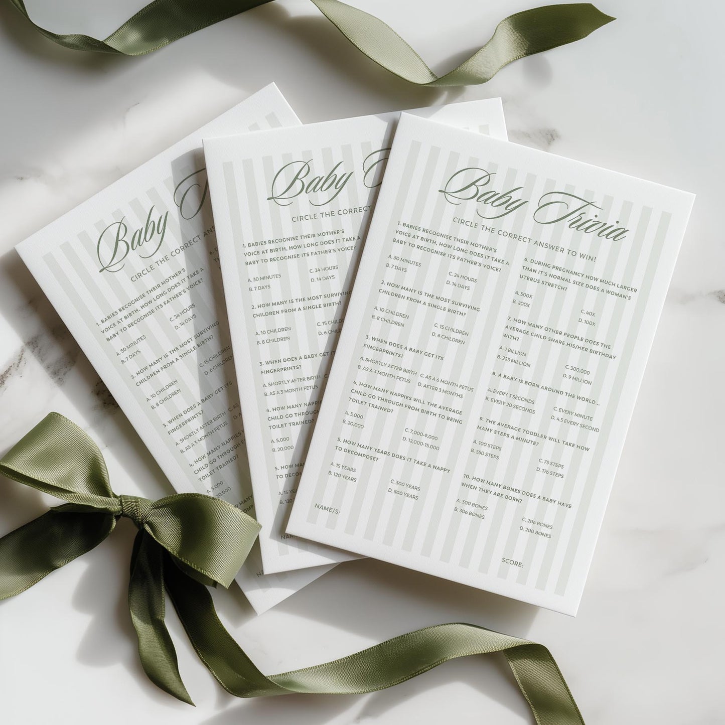 Three green stripe baby name lists on a marble surface with green ribbons.