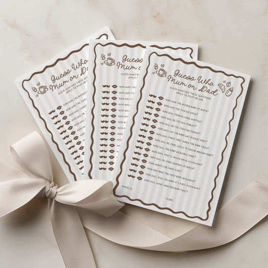 Two baby shower game cards with lip prints and text, tied with a ribbon on a beige background.