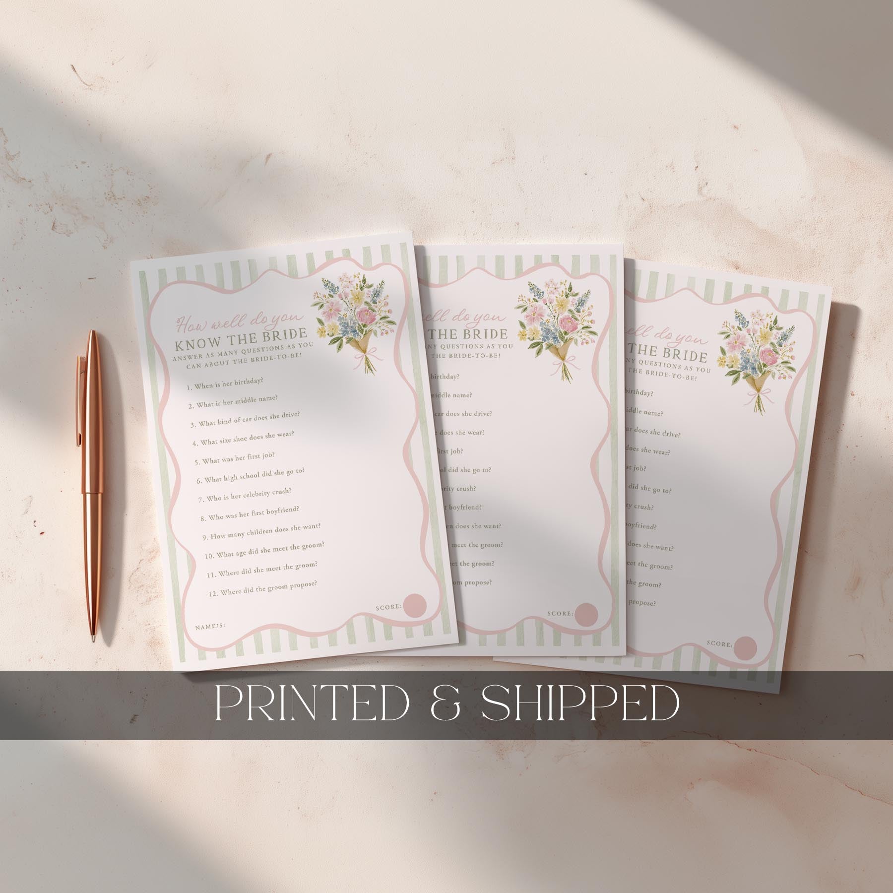 Three wedding cards with floral designs on a marble surface, accompanied by a pen.
