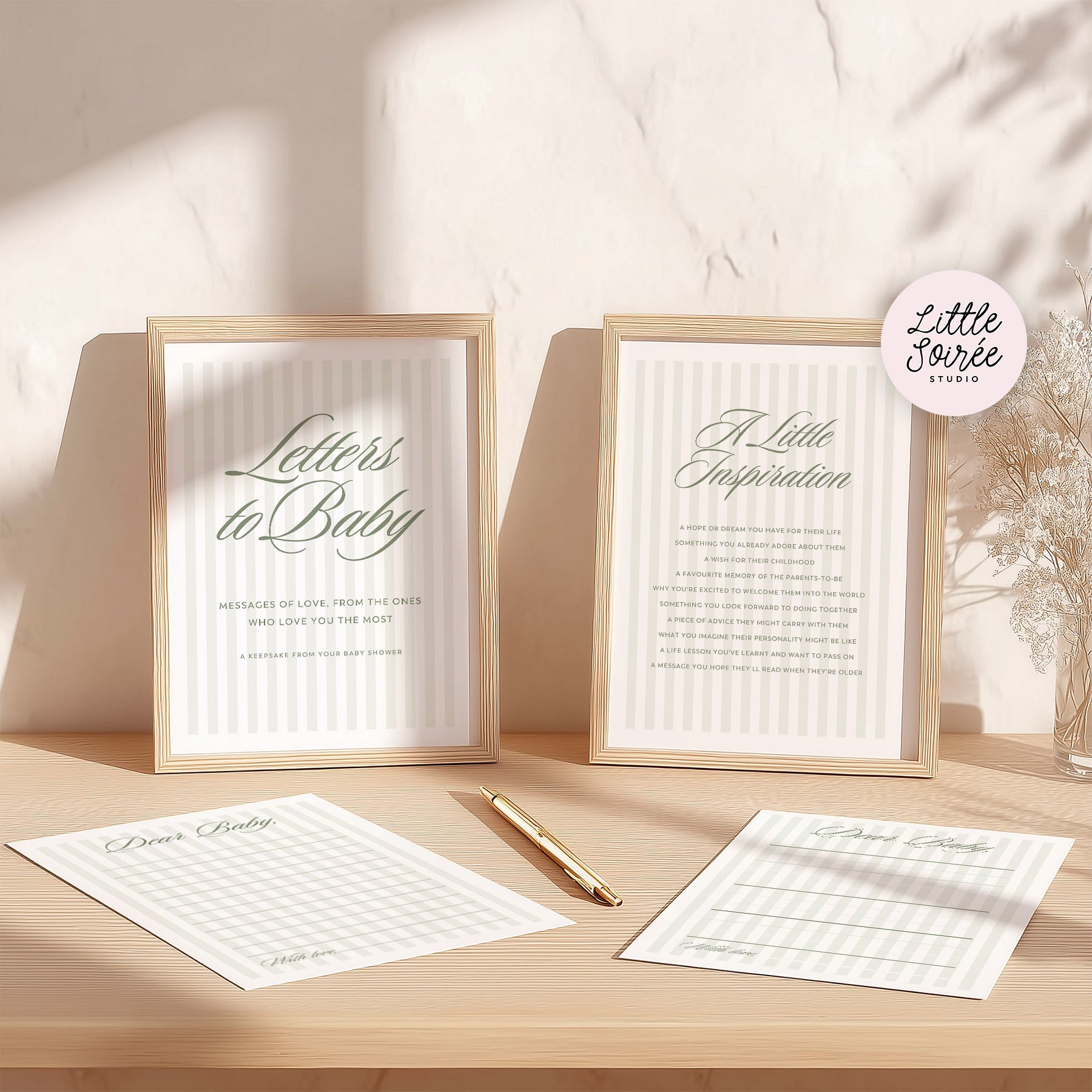 Two framed prints with text and a bow design on a wooden surface with stationery items.