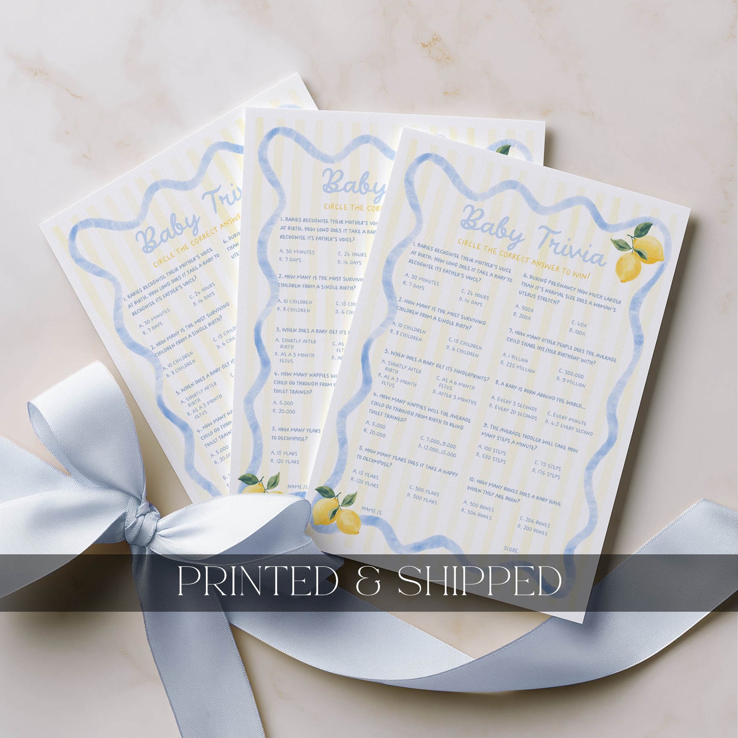 Three baby shower prediction and advice cards with a lemon theme on a beige surface with a gray ribbon.
