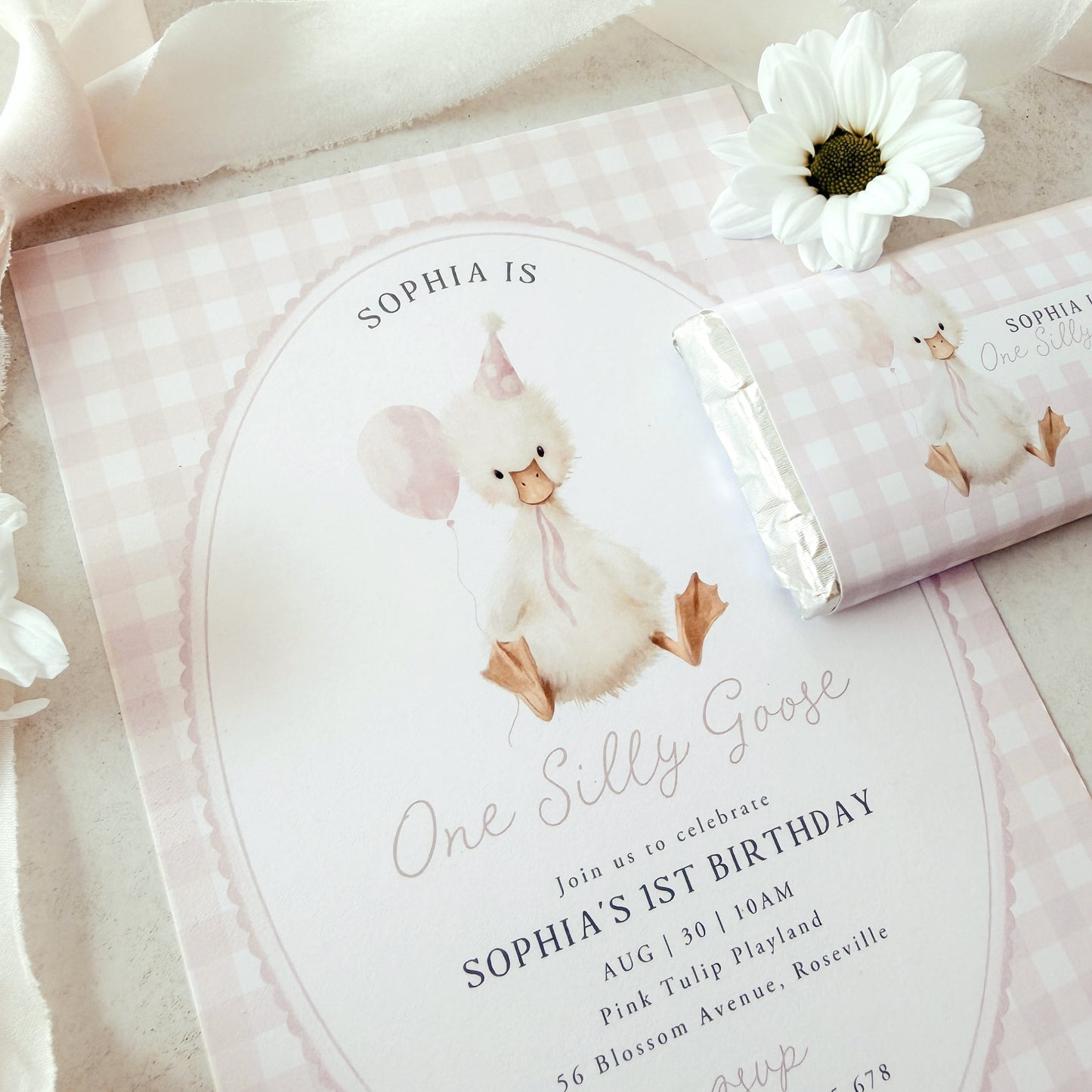 Invitation card with a goose illustration and text for a birthday celebration, accompanied by a matching swaddle blanket.