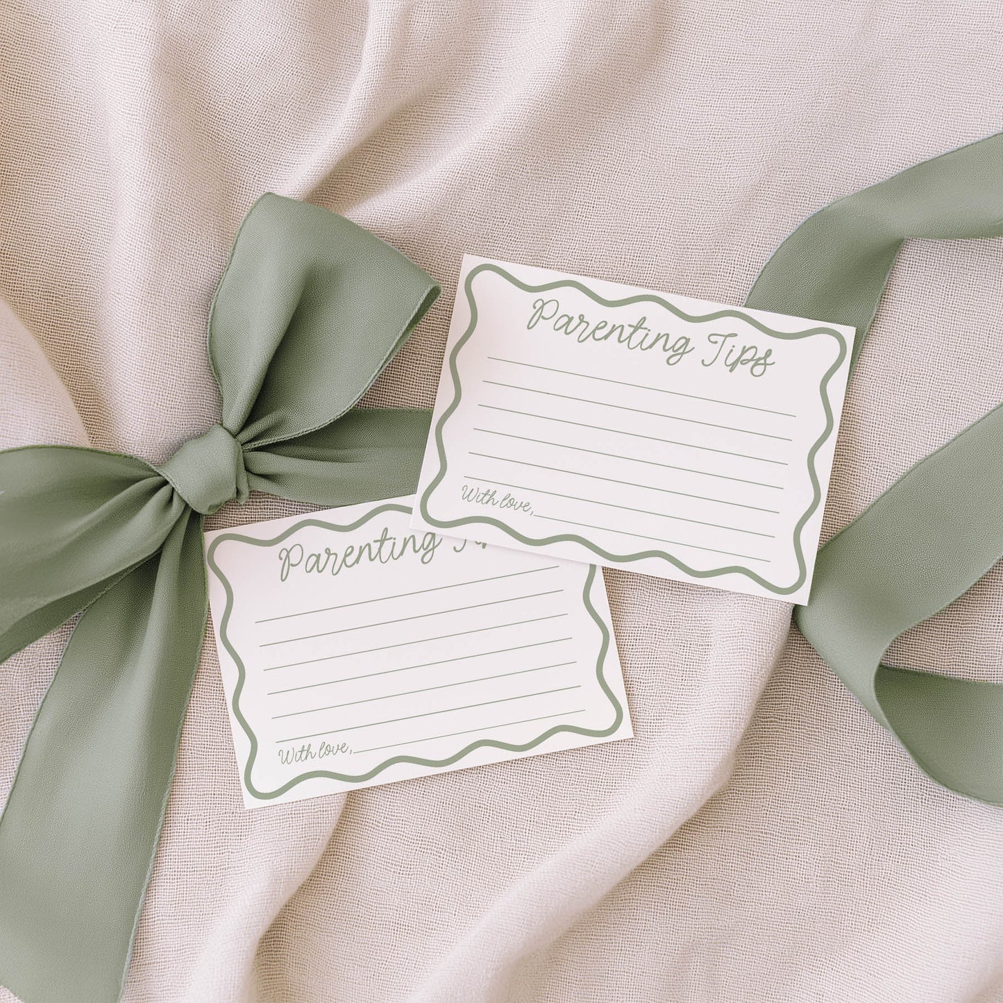 Two family tradition cards with green ribbons on a beige fabric background