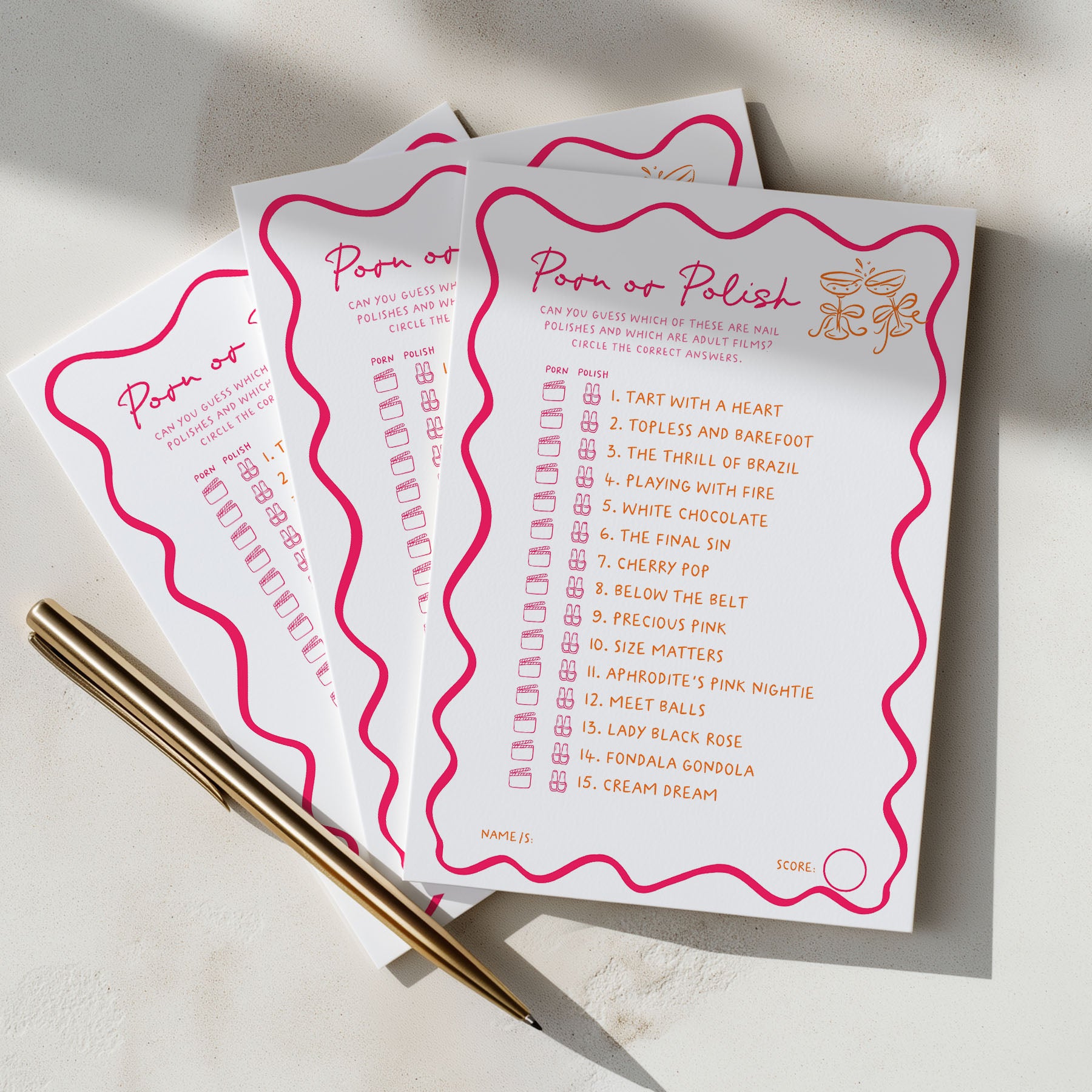 Three white game cards with pink wavy borders and gold text, arranged on a light surface with two gold pens. The cards read 'Porn or Polish' and show a list of romantic phrases to circle.