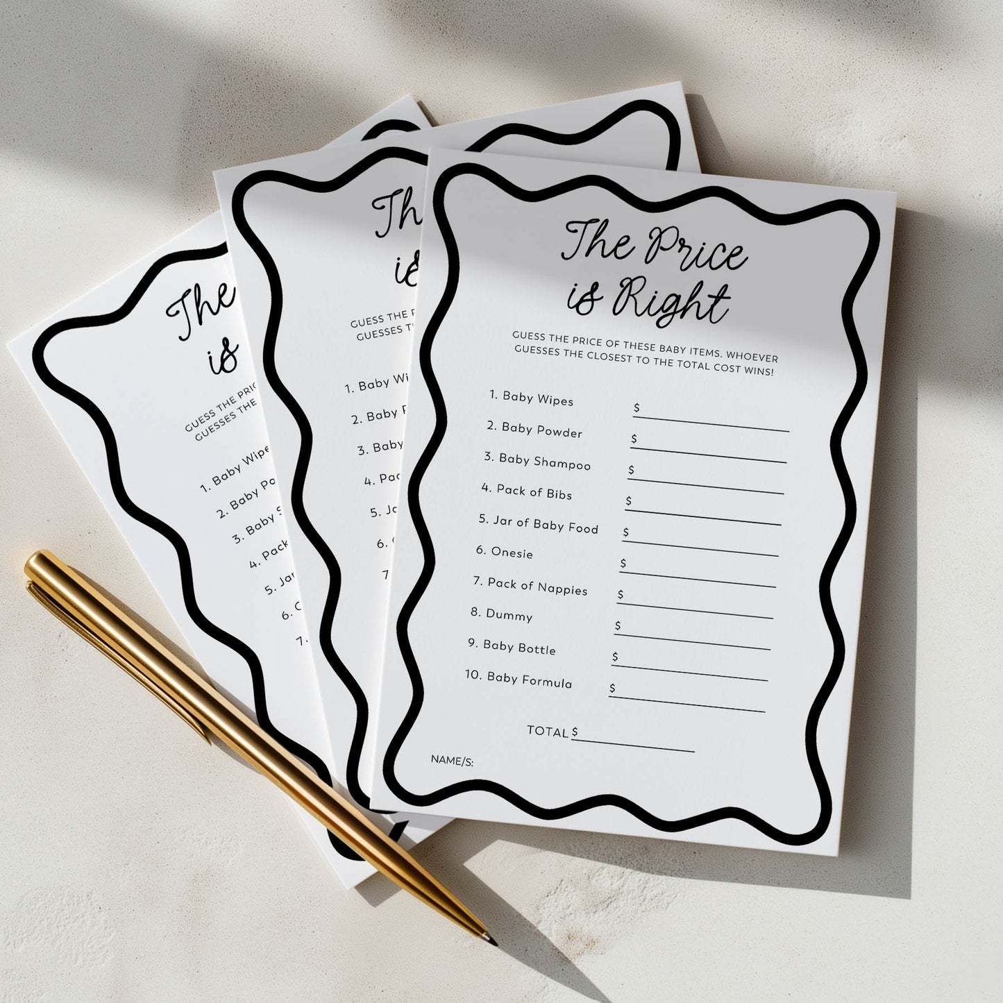 Three 'The Price is Right' game cards for a baby shower on a light surface with a gold pen.