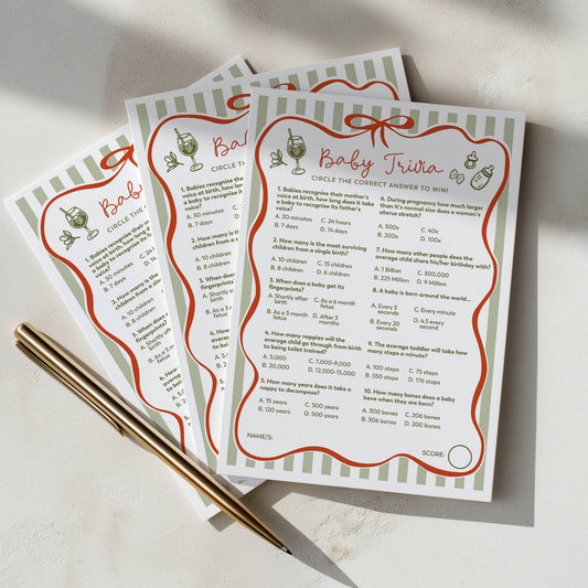 Three ciao baby baby trivia cards with a pen on a light surface green and red