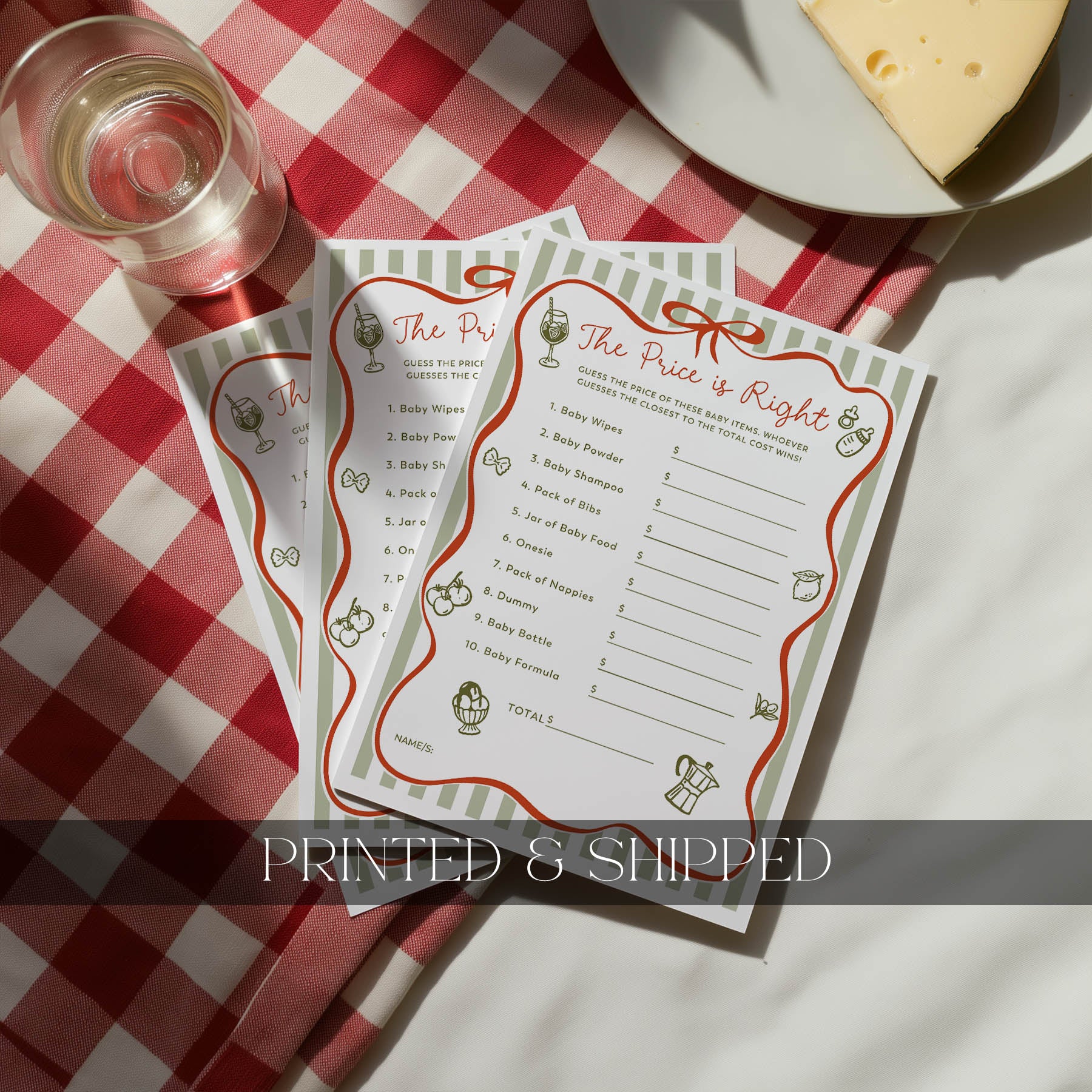 Two 'The Price is Right' game sheets on a red and white checkered tablecloth with a glass of wine and cheese.