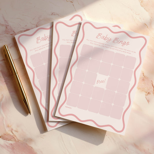 Pink Wavy Baby shower bingo cards with a pen on a marble surface