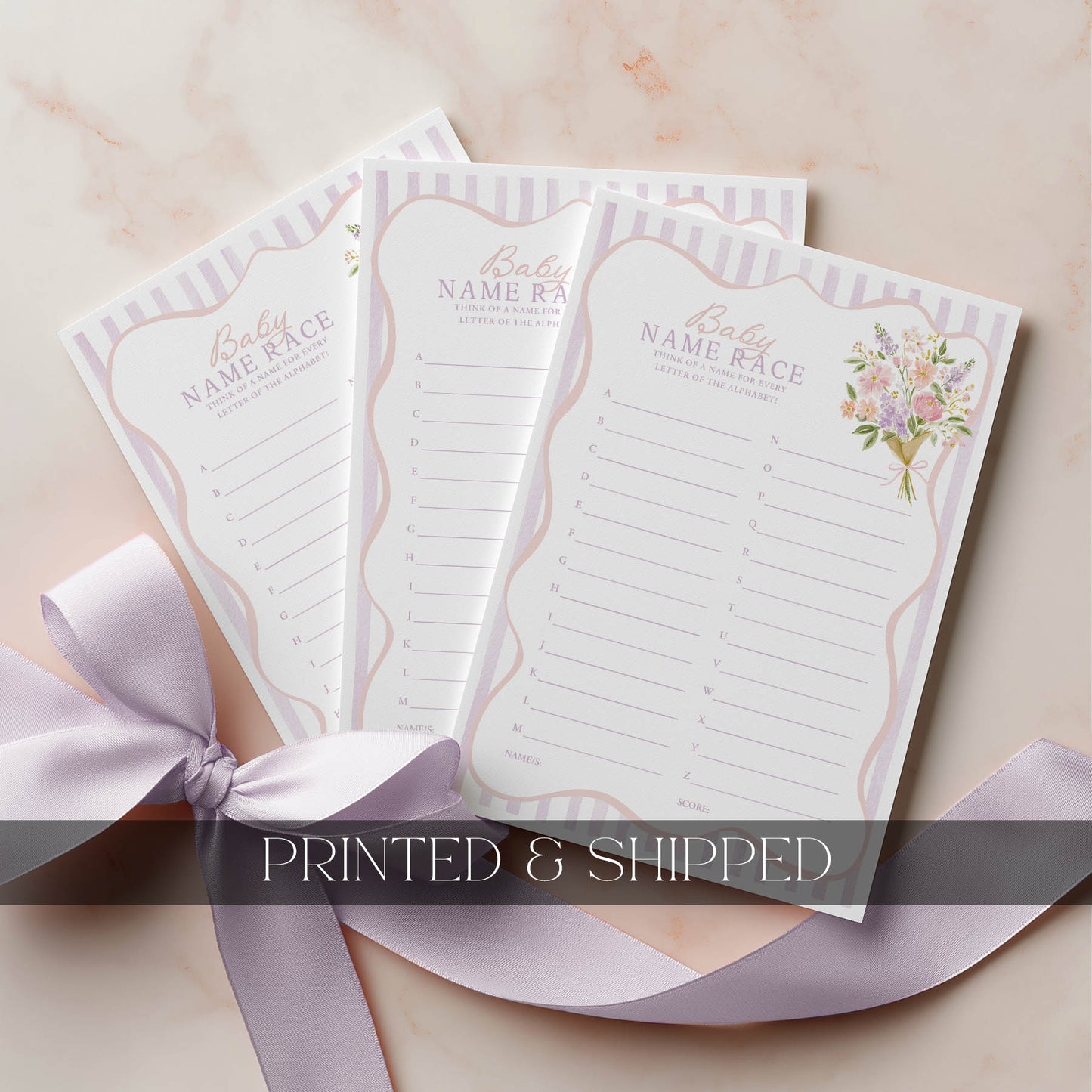 Three baby name race cards with floral design on a beige surface with a pink ribbon.