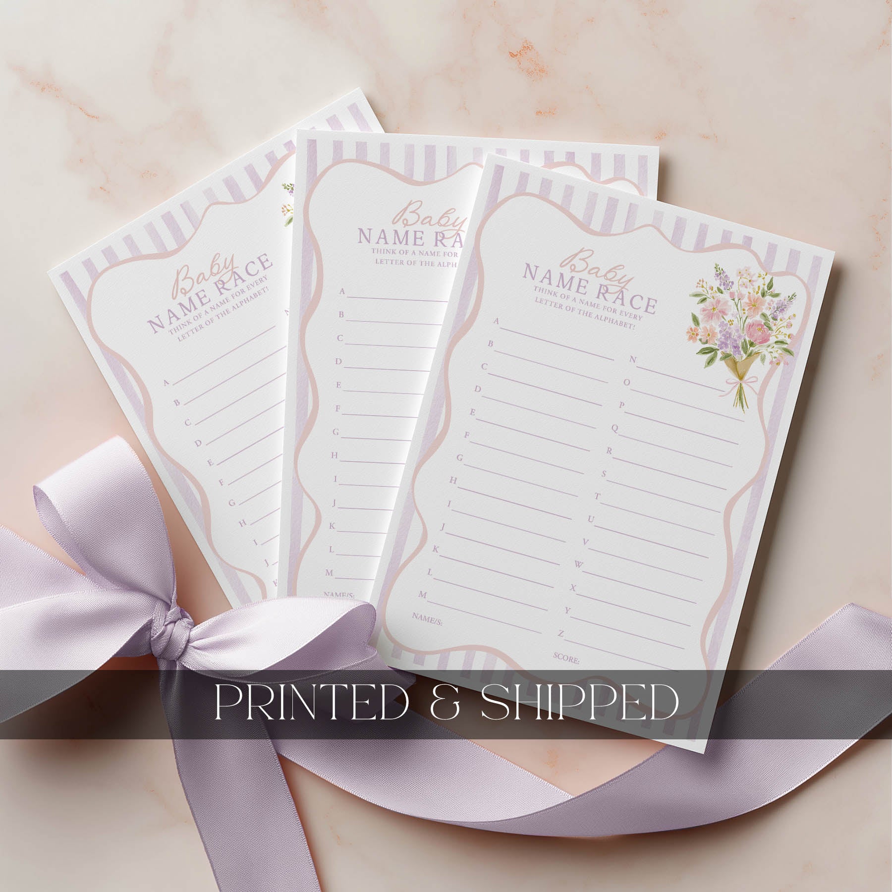 Three baby name race cards with floral design on a beige surface with a pink ribbon.