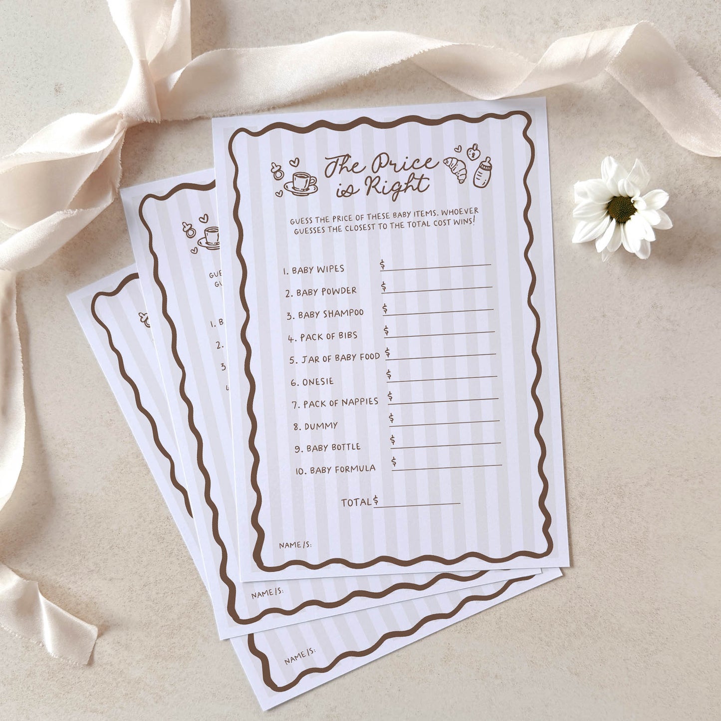 Two 'The Price is Right' baby shower game sheets on a beige surface with ribbons and a flower.