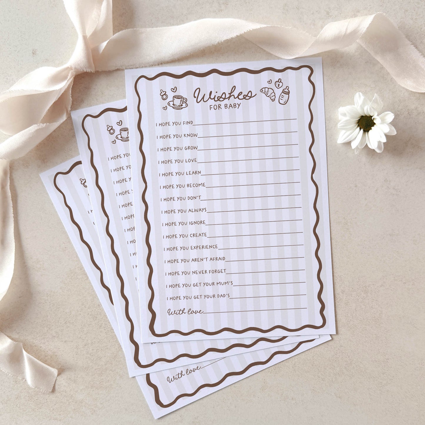 Two sheets of paper with a baby shower wish list on a beige background with ribbons and a flower.