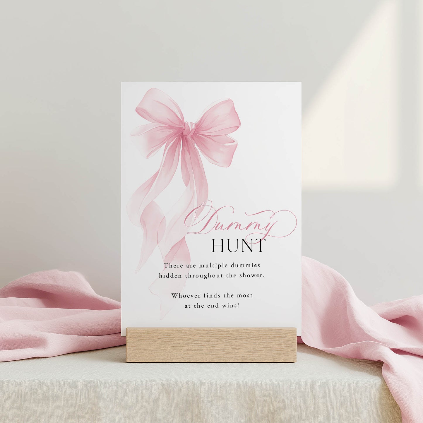 Pink bow and card with 'Dummy Hunt' text on a light background