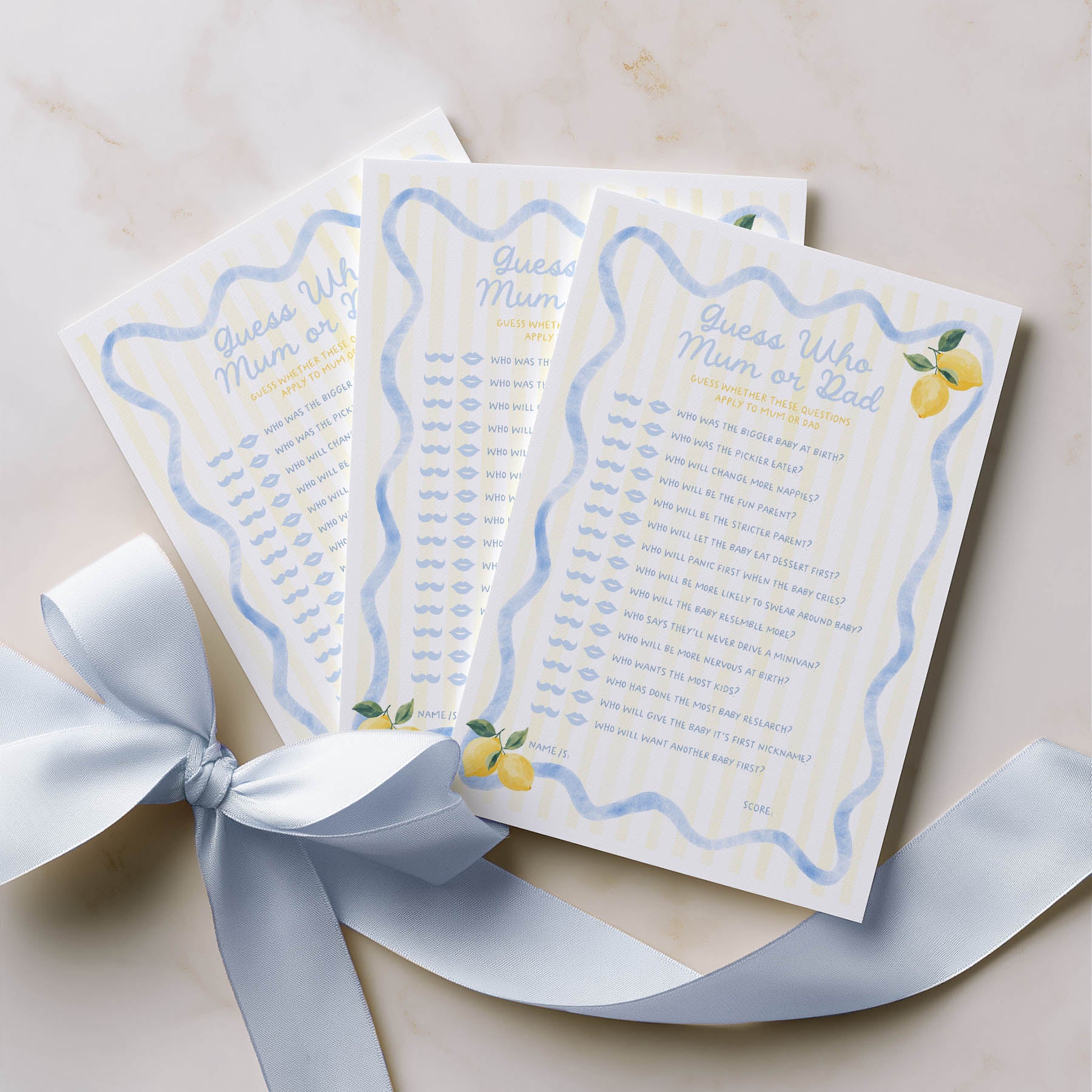 Three baby shower games with lemon illustrations on a beige surface with a white ribbon.