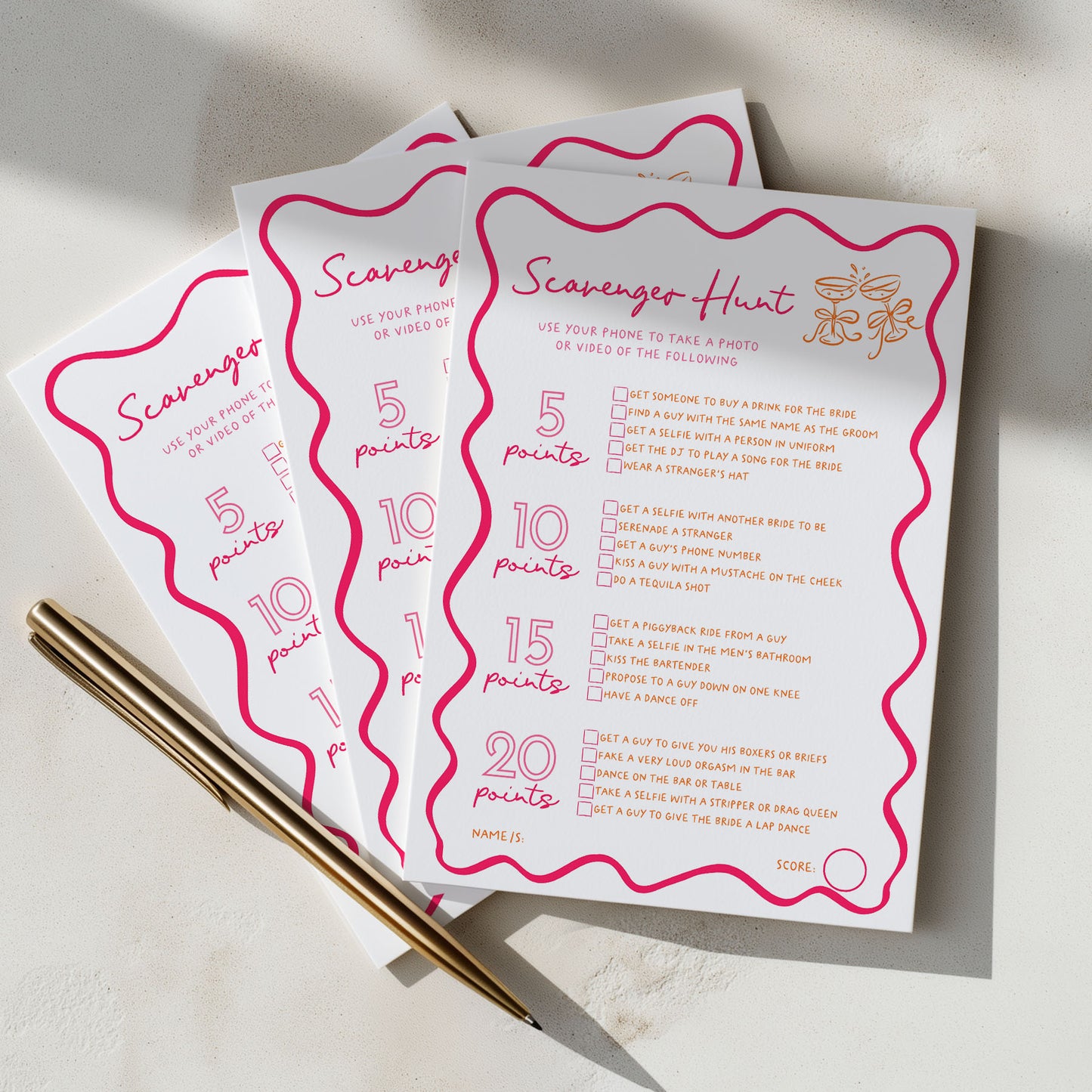 Three printed game cards for a 'Scavenger Hunt' game fanned out on a light surface, with two gold pens resting on the left side.