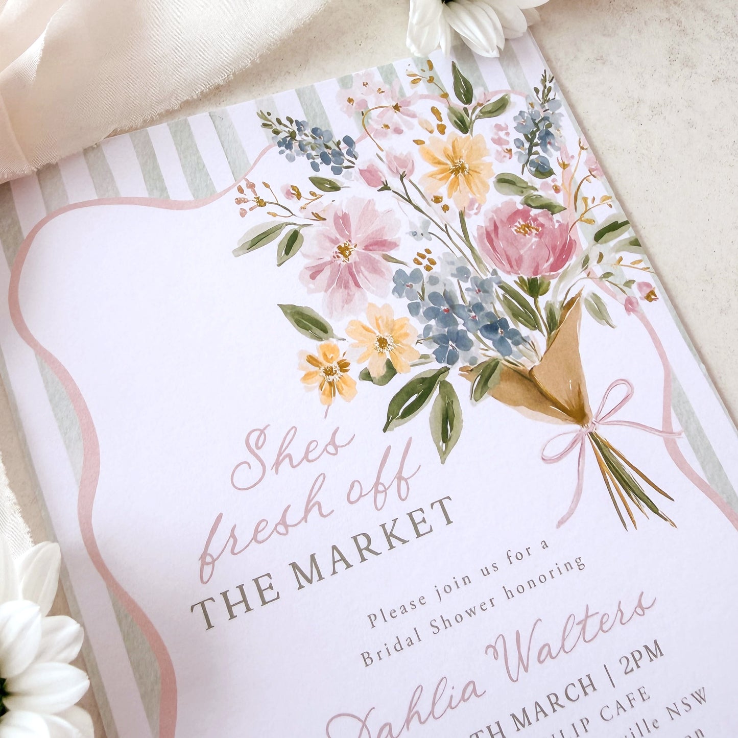 Bridal Shower invitation with blue ribbon and ring on a beige fabric background