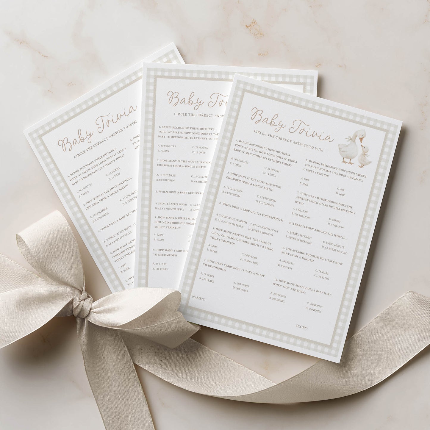 Three baby shower trivia cards with a decorative bow on a light background