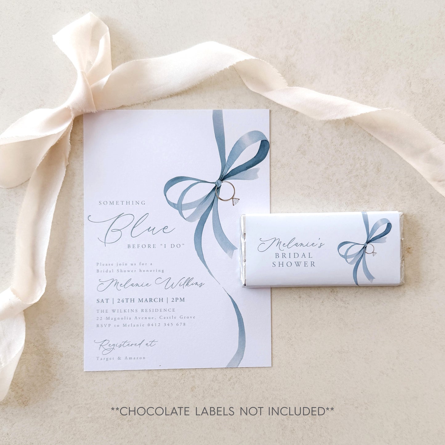 Bridal shower invitation with blue ribbon design and a chocolate bar labeled 'Melanie's Bridal Shower' on a beige background.