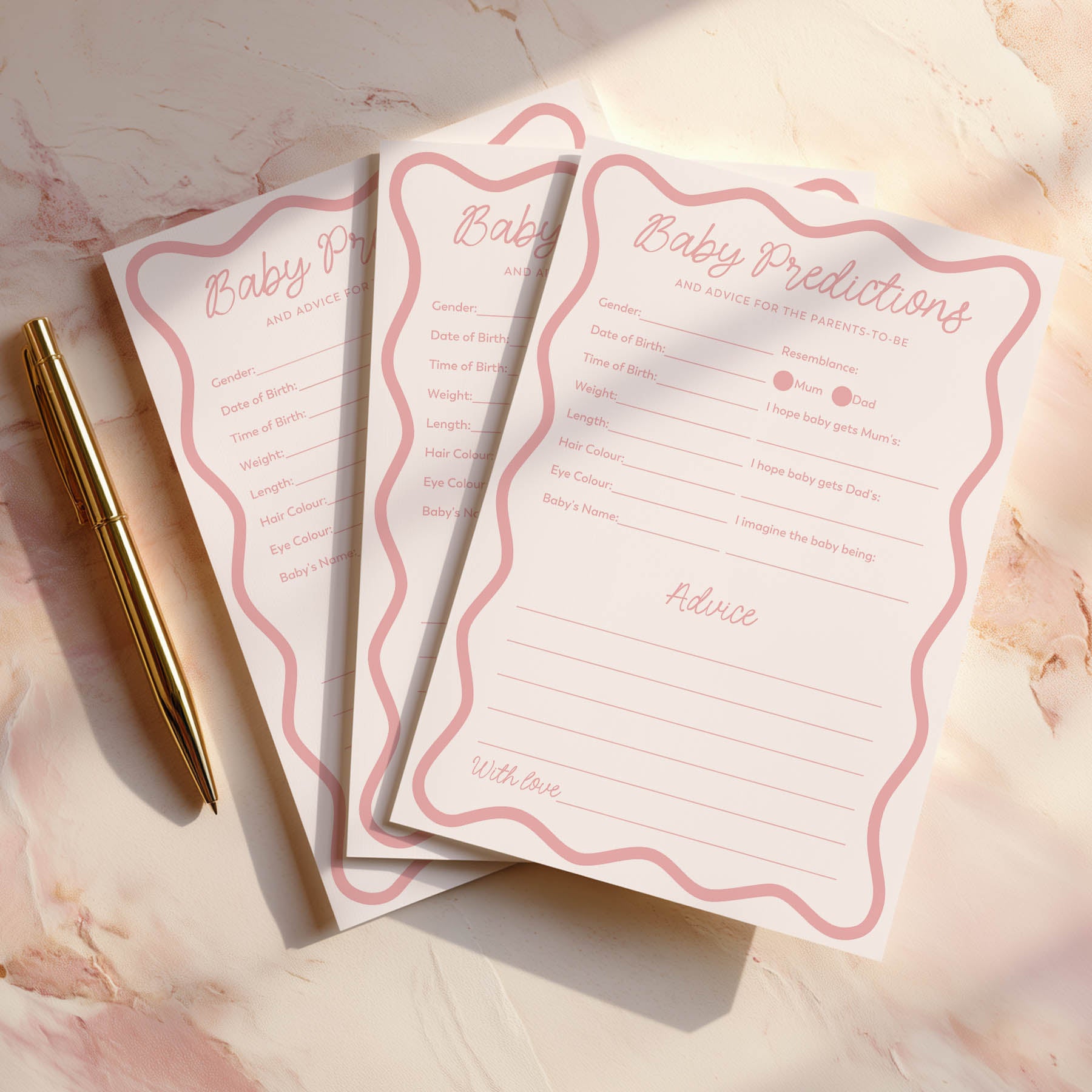 Pink Wavy Baby shower prediction cards with a gold pen on a decorative surface
